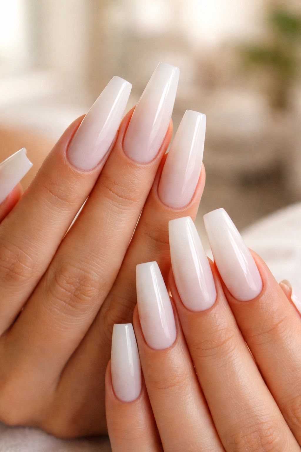 Long coffin milky white nails with soft glow in a salon-like setting