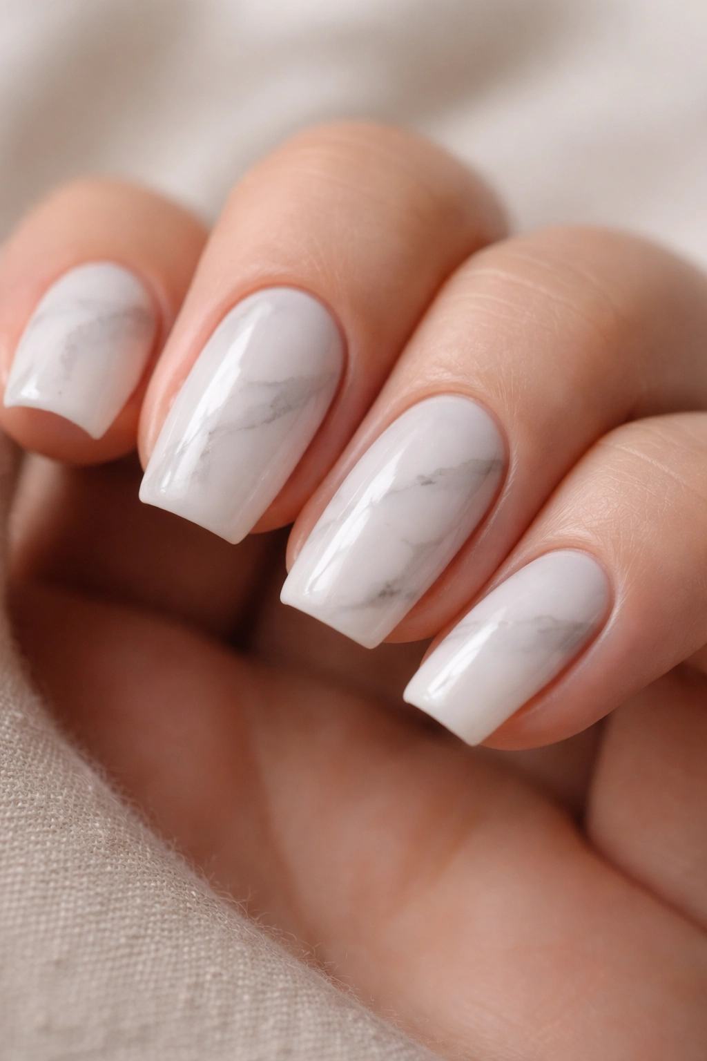 Close-up of short coffin nails with subtle milky white marble and gray veins