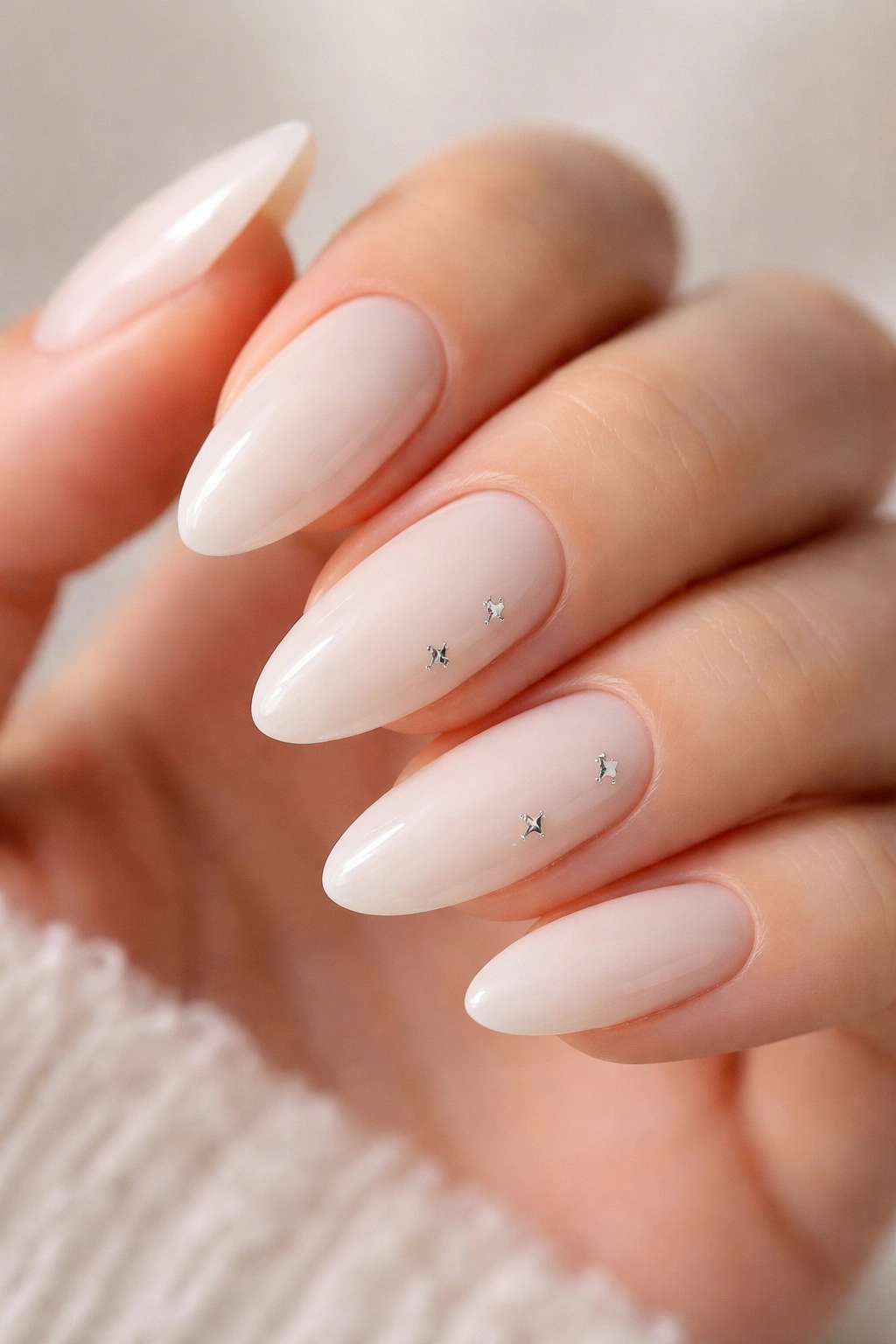 Milky white almond nails with tiny silver stars on a couple of nails
