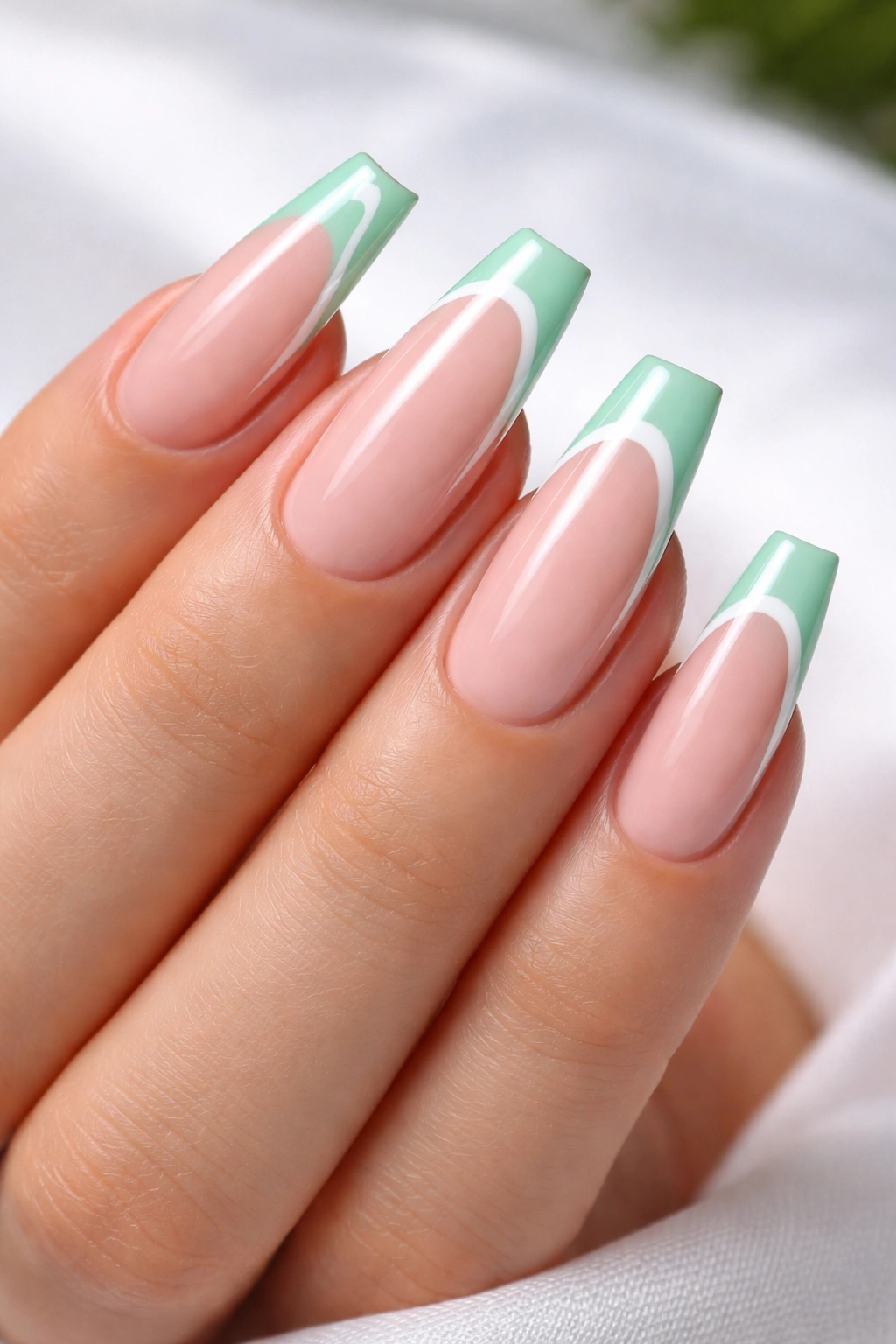 Close-up of coffin nails with mint and white double-line tips on a nude base.