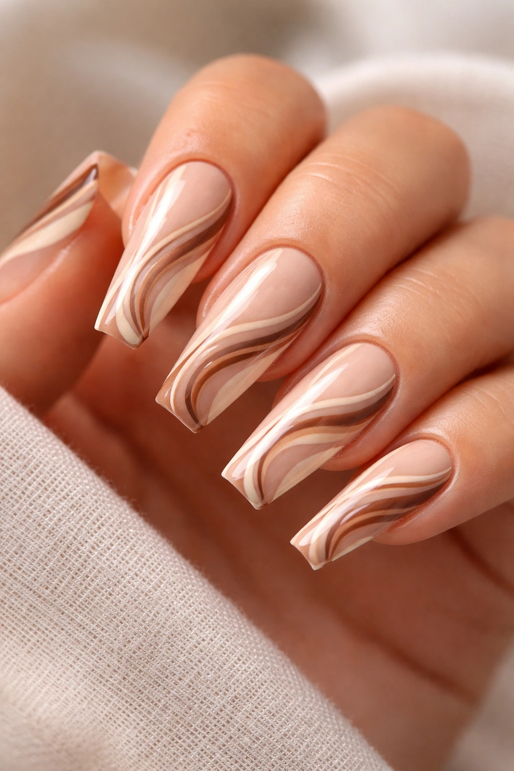 Coffin nails with mocha and cream swirl patterns on a sheer nude base.