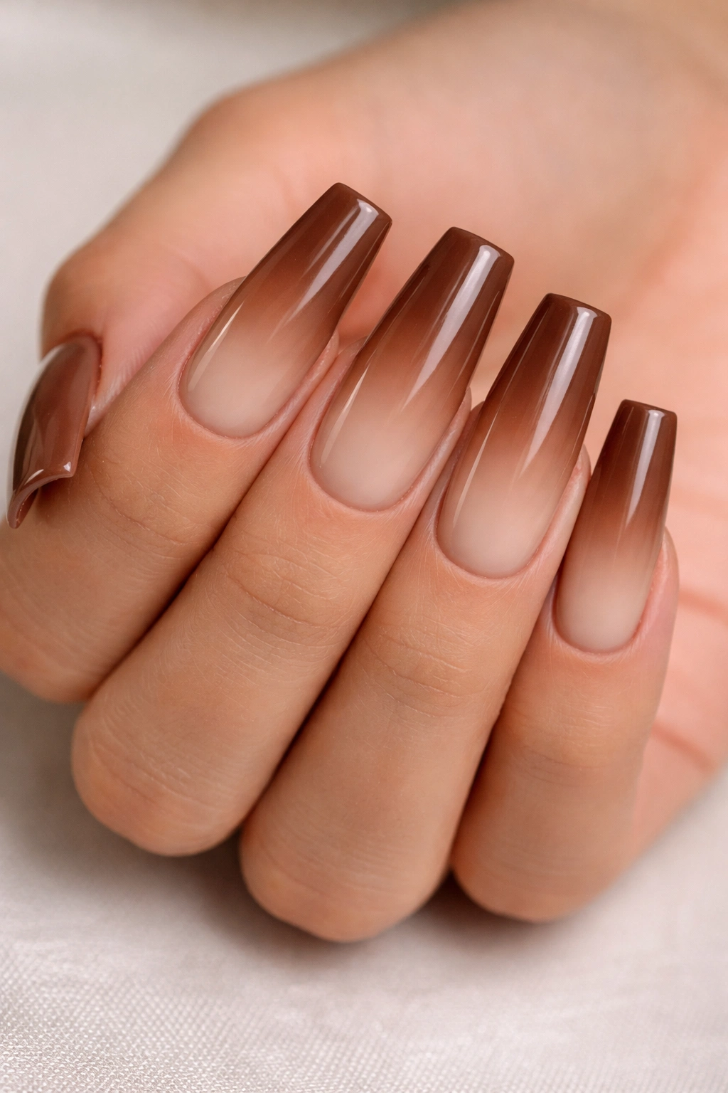 Close-up of mocha to latte brown ombre coffin nails in studio lighting