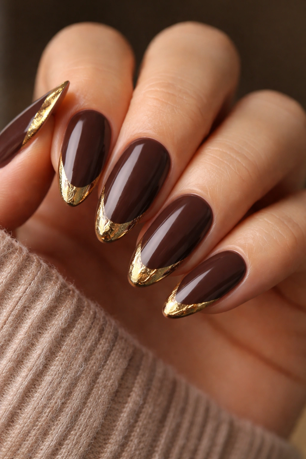 Close-up of almond nails in deep mocha with molten gold tips