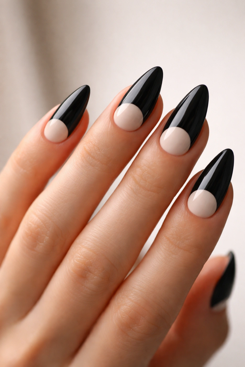 Close-up of almond-shaped nails with black and cream half-moon designs at the base