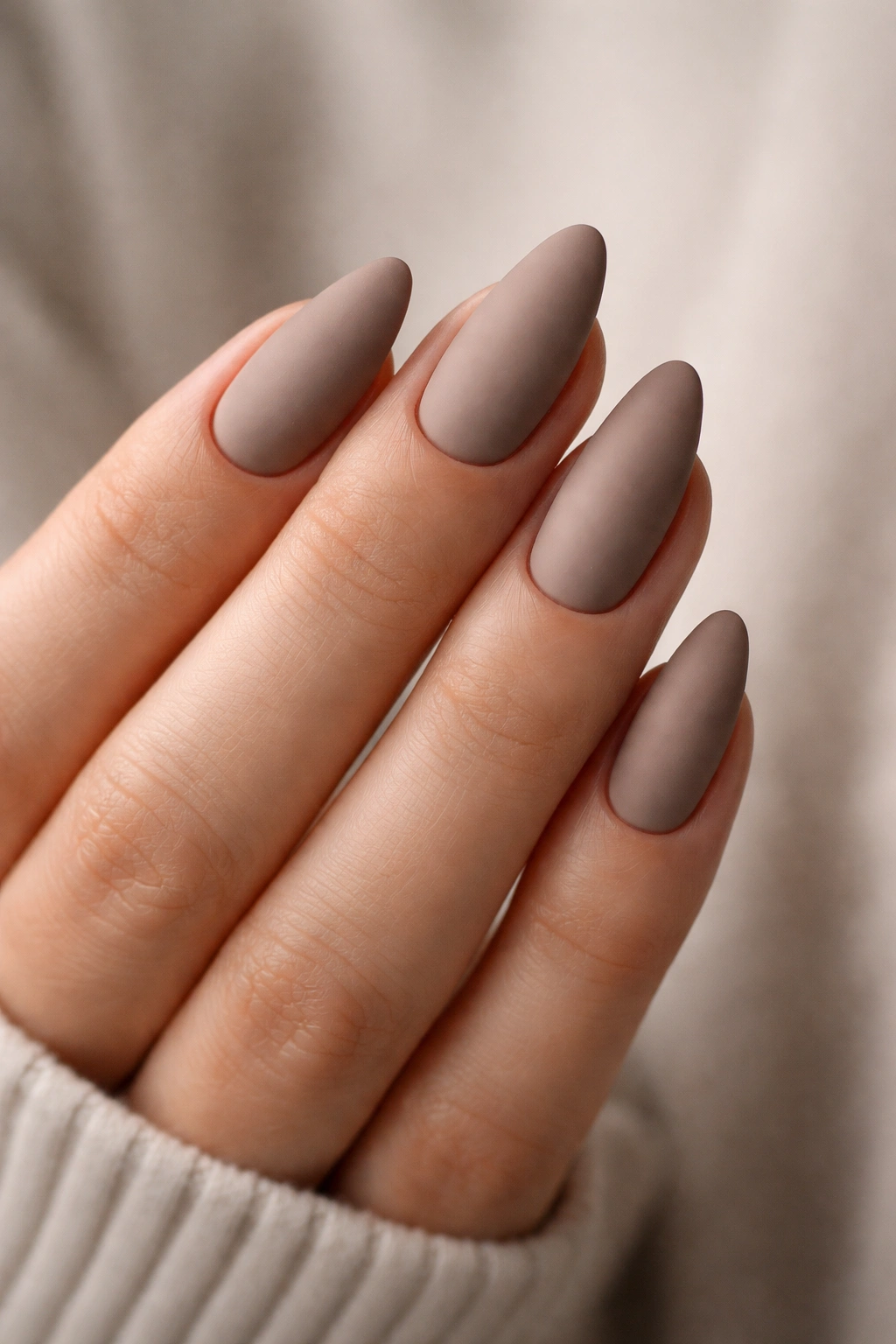 Close-up of matte taupe almond nails with velvety finish