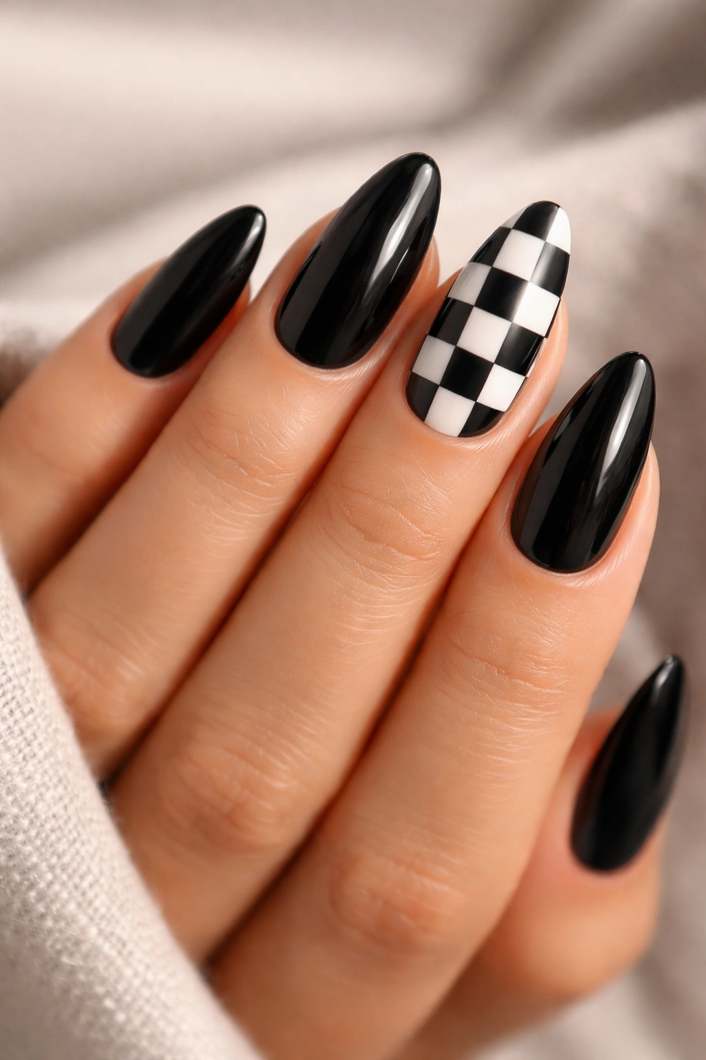 Close-up of checkerboard accent nails in black and white on almond nails