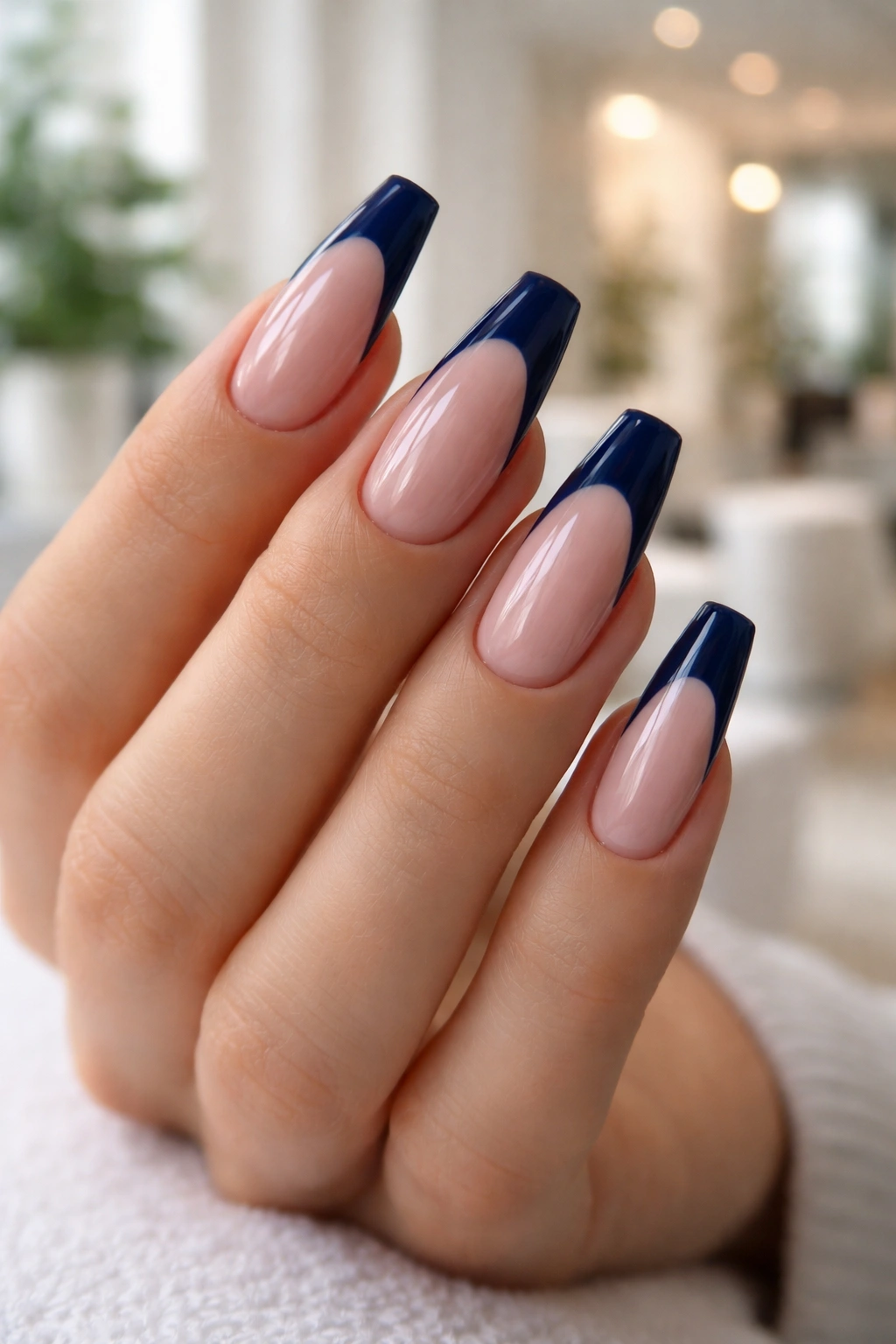 Close-up of navy blue French tip coffin nails in a salon setting