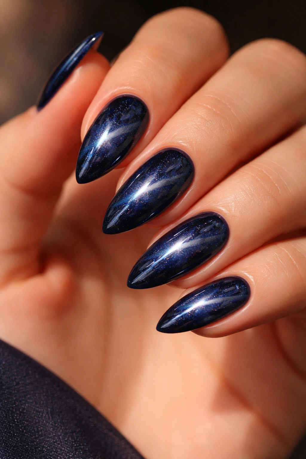 Close-up of almond nails with deep navy cat-eye shimmer