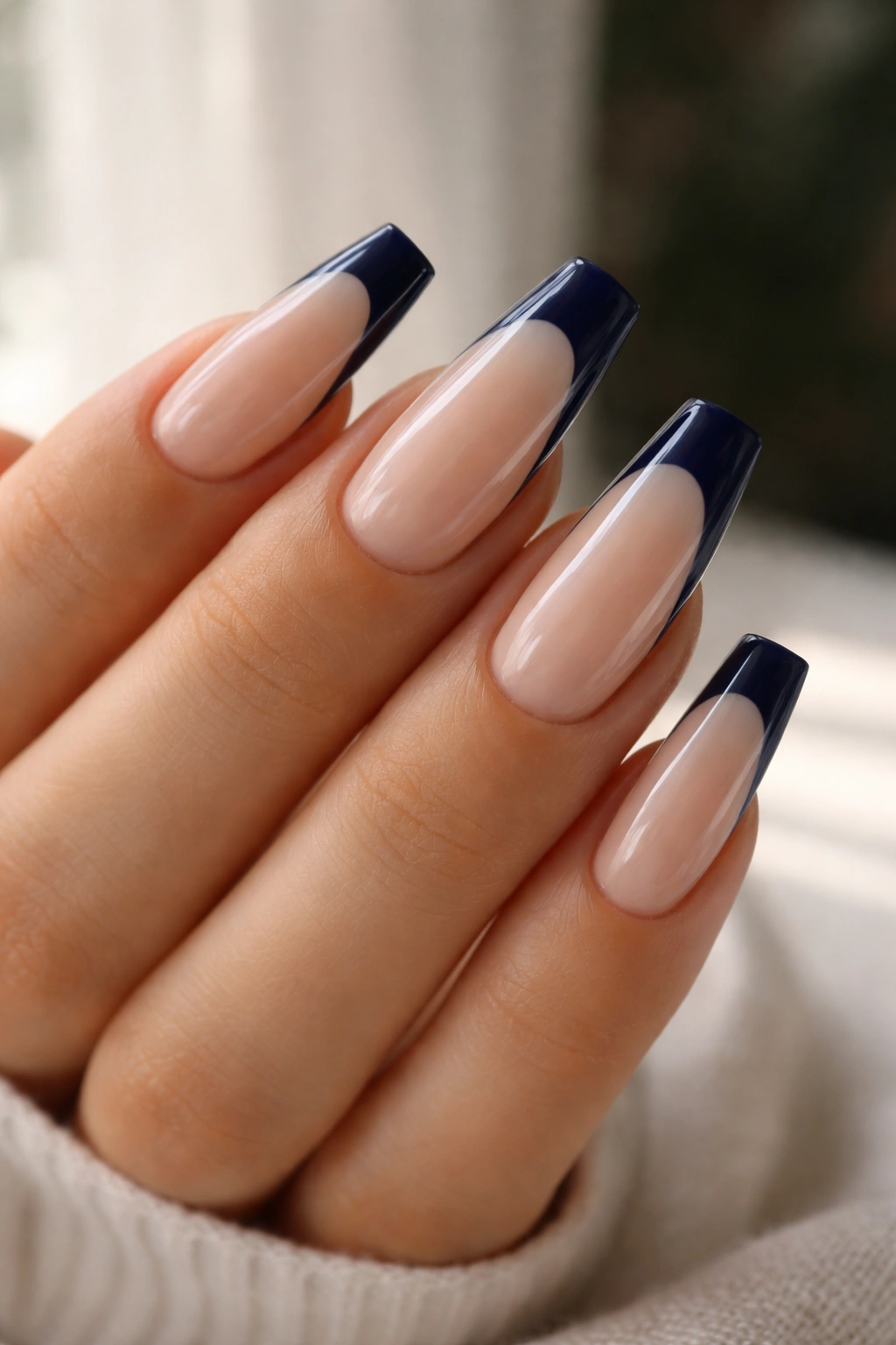 Close-up of coffin nails with navy tips and glossy nude base