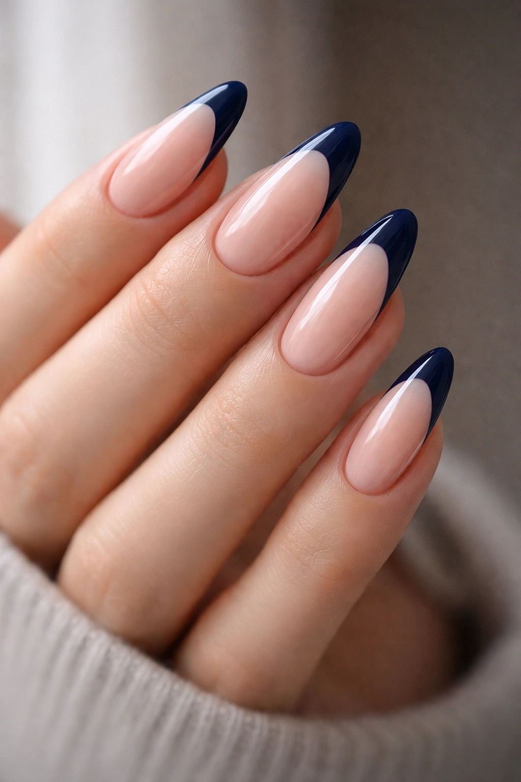 Almond nails with navy tips and a high-gloss finish on a pale base