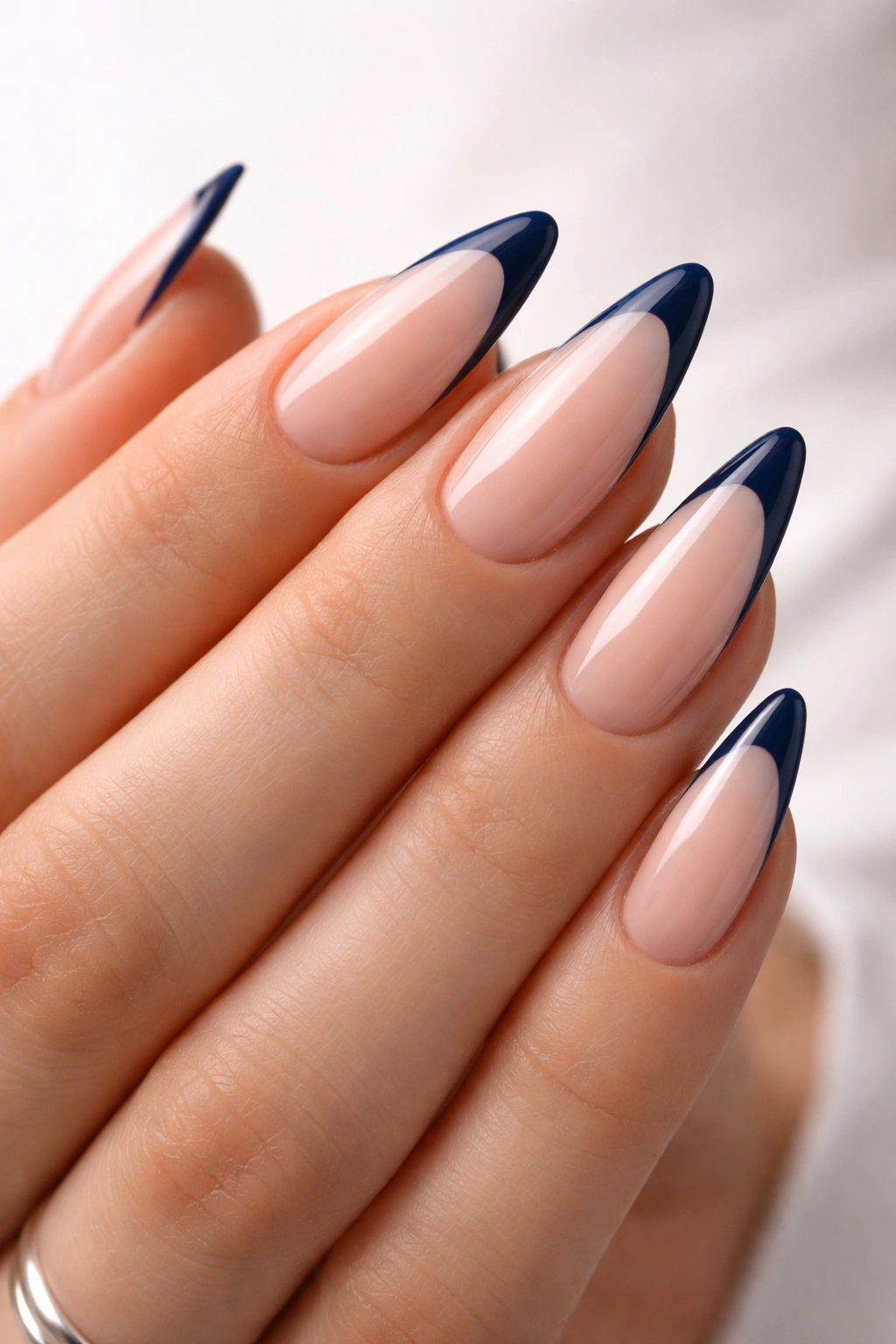 Almond nails with slim navy French tip on nude base