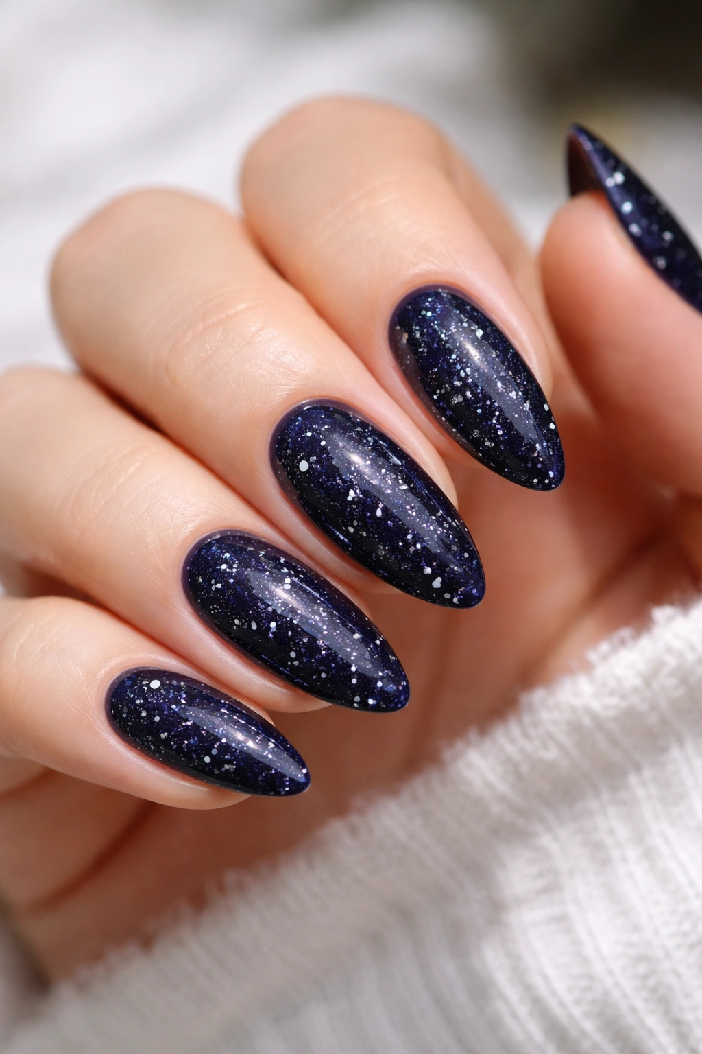 Navy glitter almond nails with tiny dots of light