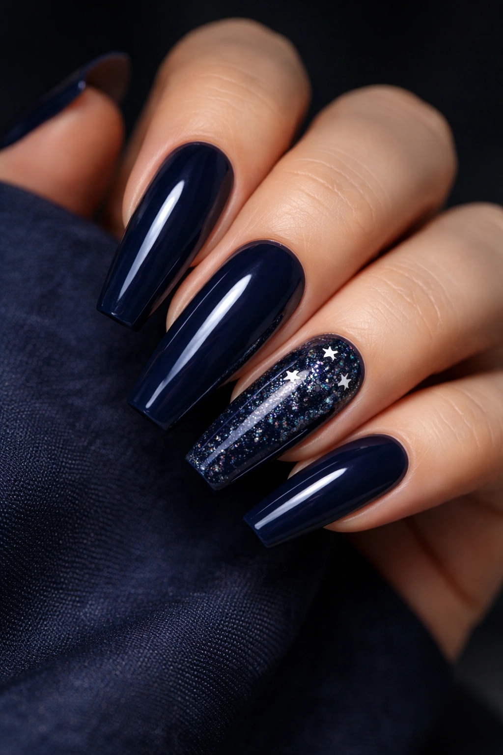 Close-up of deep navy coffin nails with constellation glitter clusters and tiny star accents