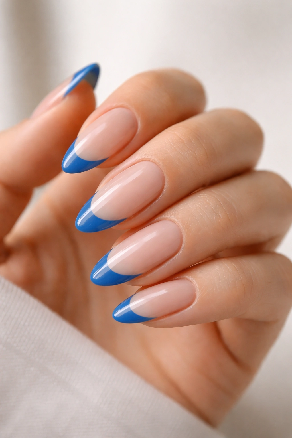 Almond nails showing negative-space blue tips with a clear base