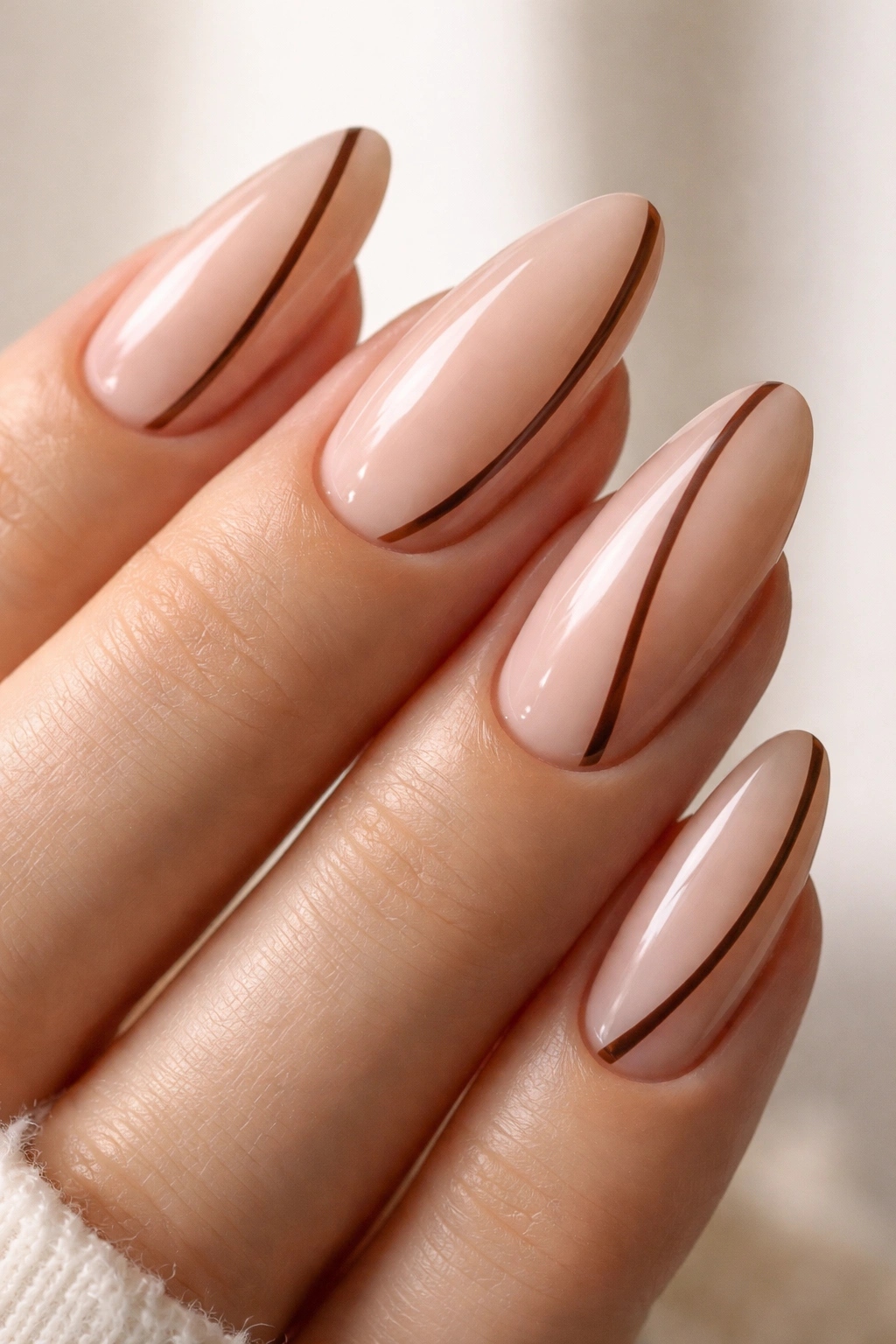 Almond nails with sheer nude base and fine brown contour line