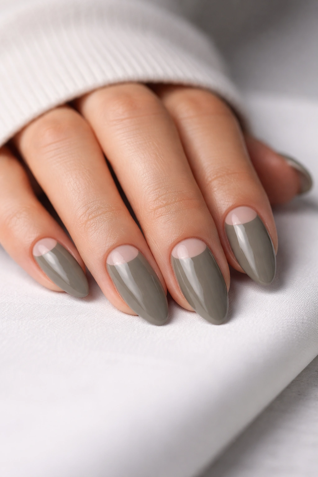 Close-up of almond nails featuring a small negative-space crescent near the cuticle on a neutral background