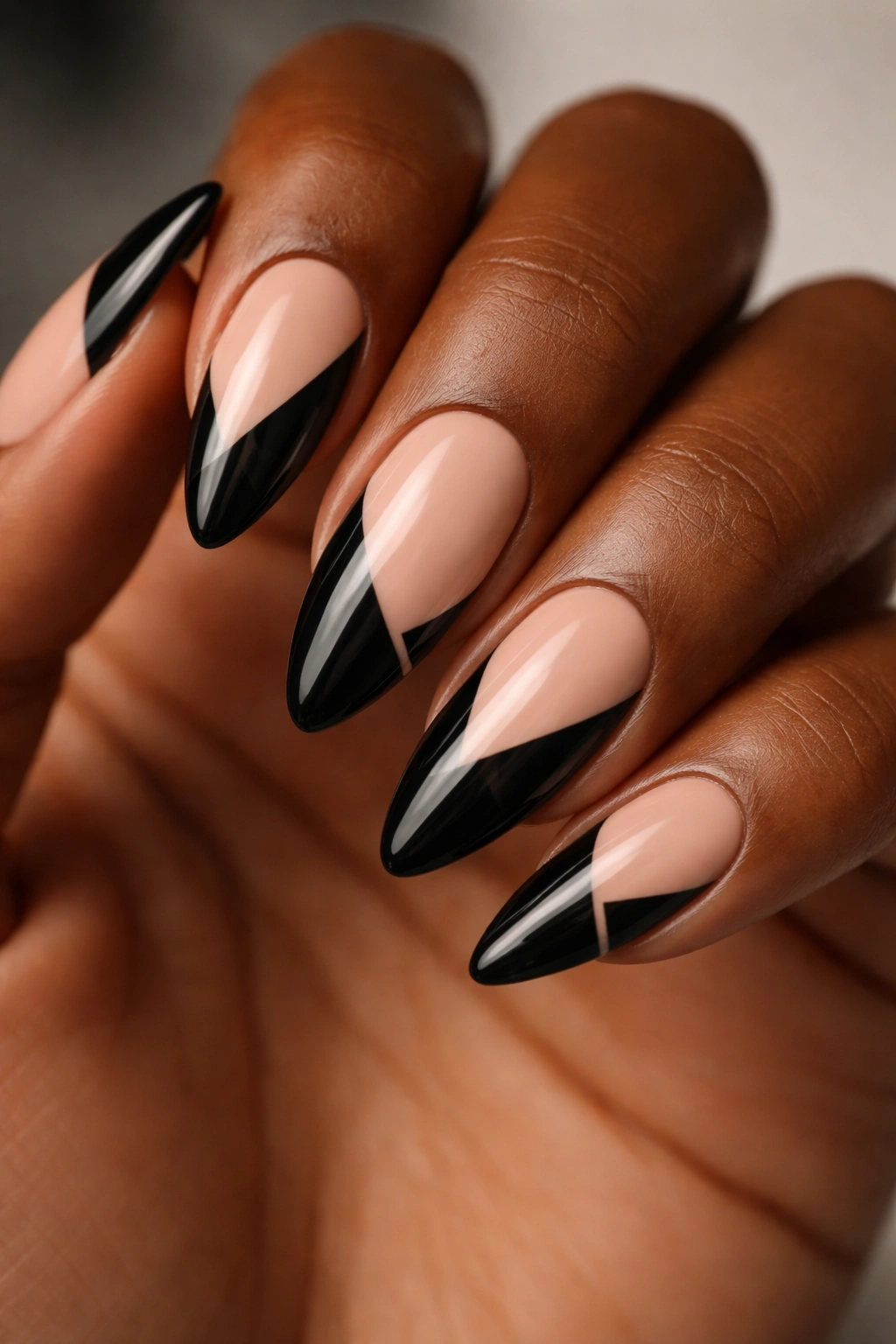 Close-up of almond nails with black negative-space cutouts on nude base