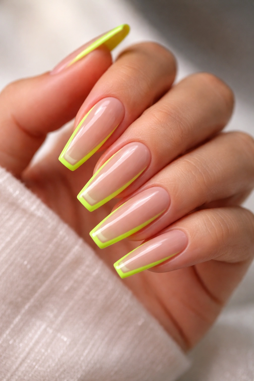 Close-up of neon lime outline coffin nails on a nude base