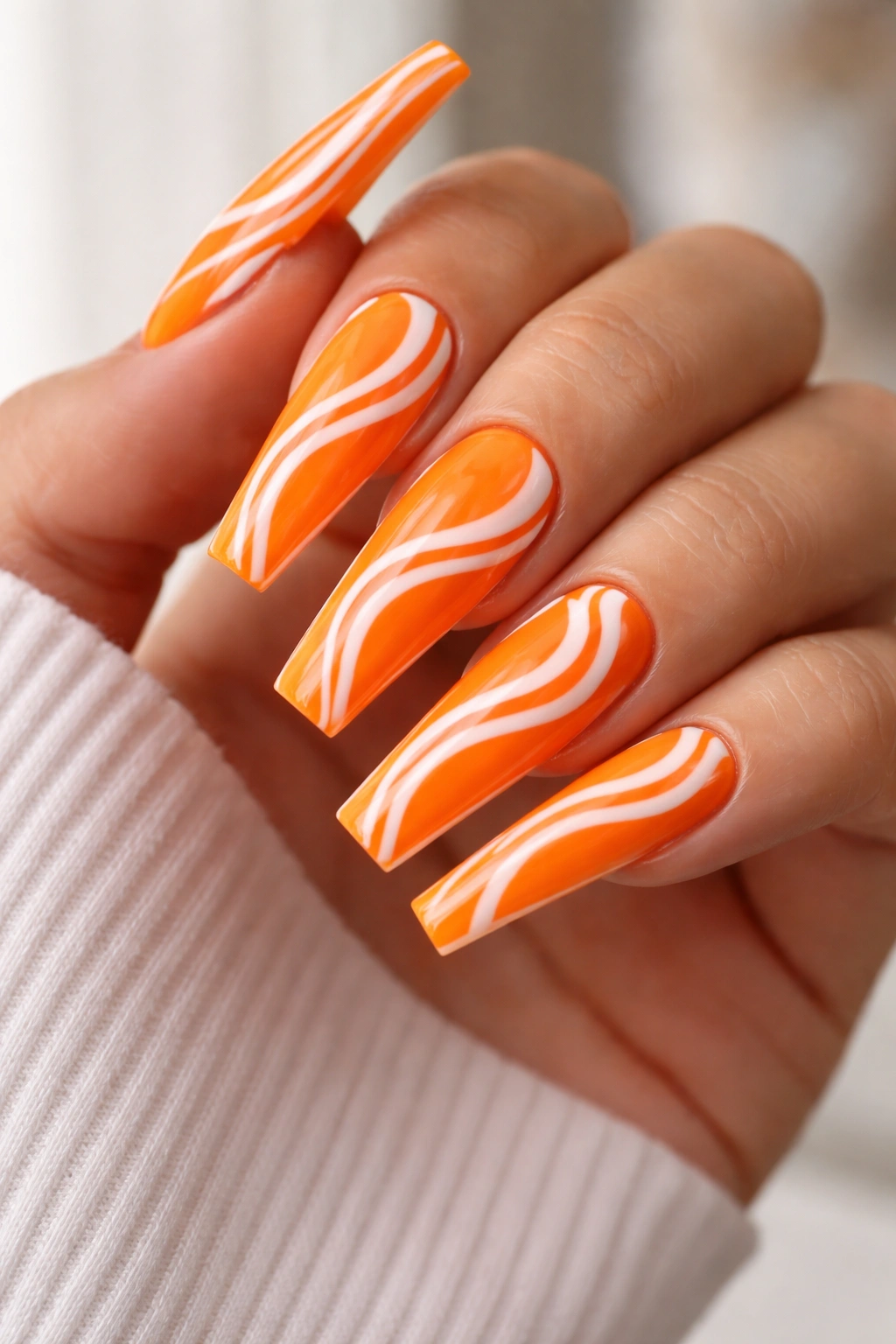 Neon orange coffin nails with white swirl patterns