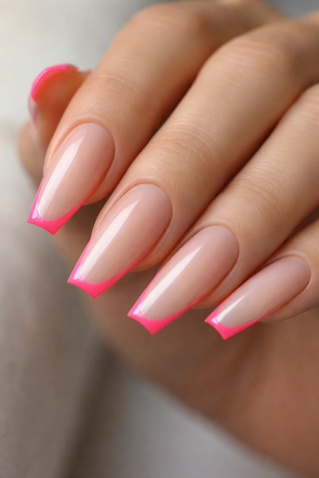 Close-up of neon pink micro French nails on a milky nude base in coffin shape