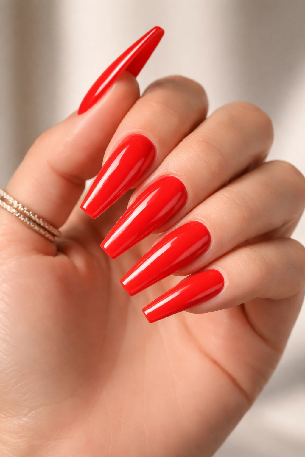 Neon poppy red coffin nails on a medium-to-long shape with high-gloss finish