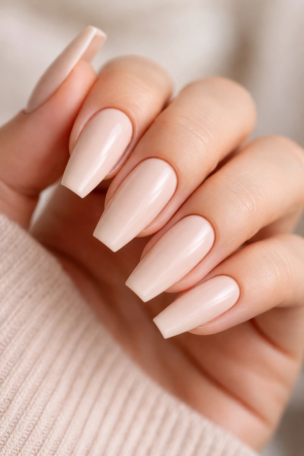 Close-up of neutral coffin nails with creamy nude matte polish and clean cuticles