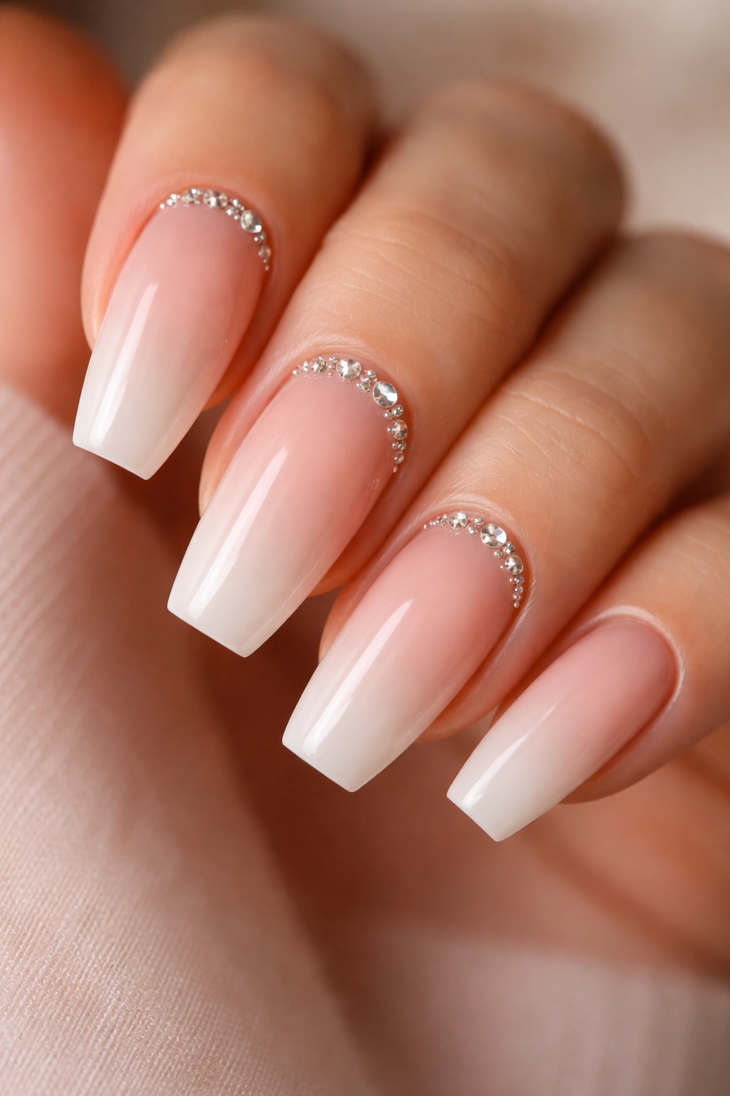 Close-up of nude-blush ombre nails with tiny cuticle crystals on two nails