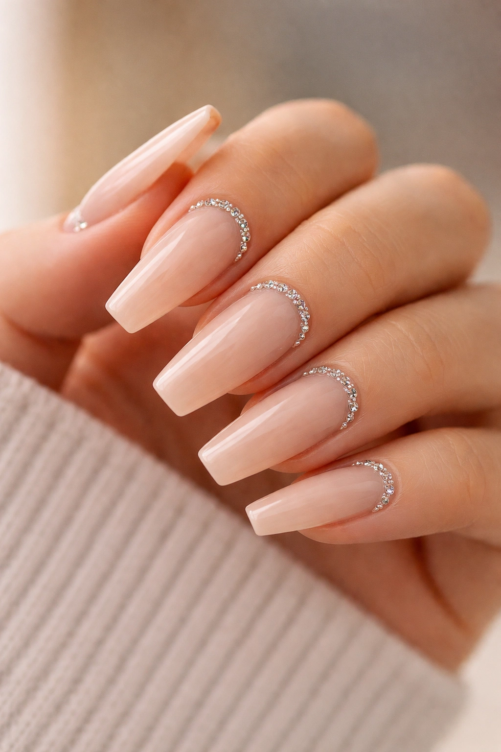 Nude coffin nails with a curved crystal crescent at the cuticle