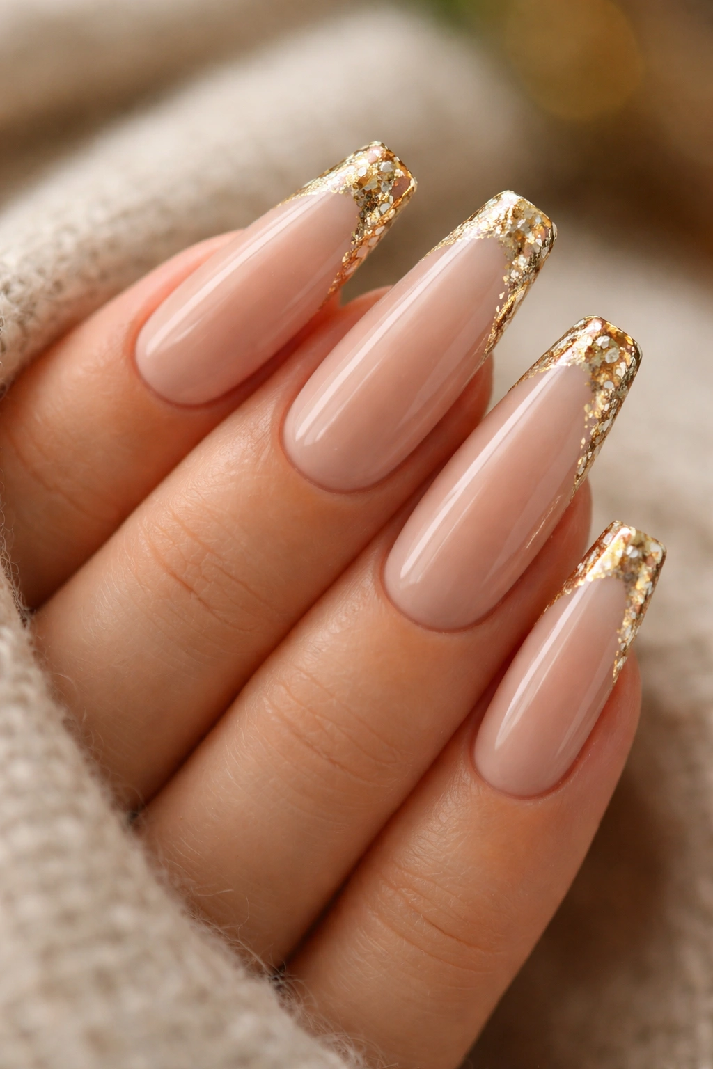 Close-up of nude coffin nails with irregular gold foil edges