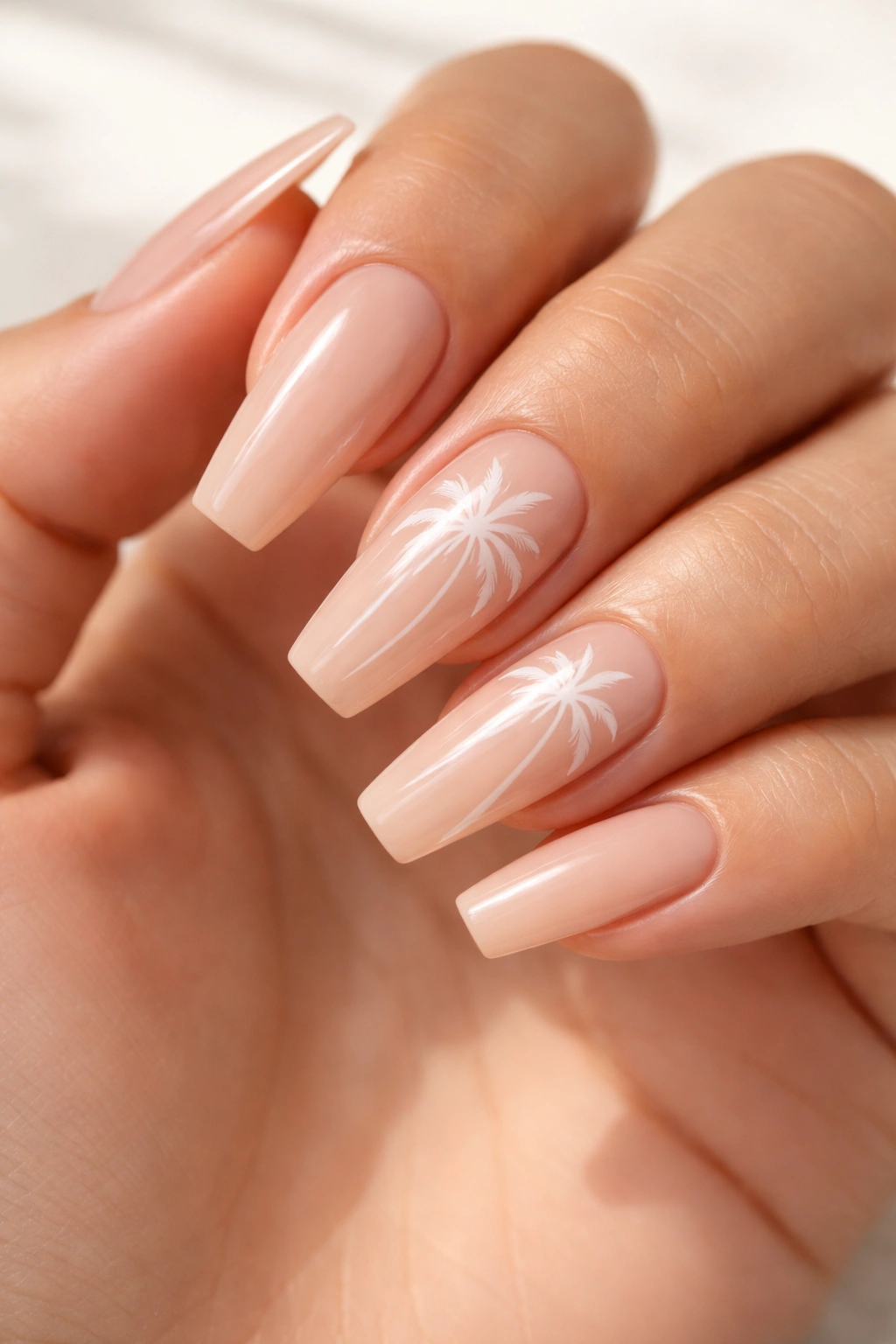 Close-up of nude coffin nails with white palm silhouettes on a neutral base