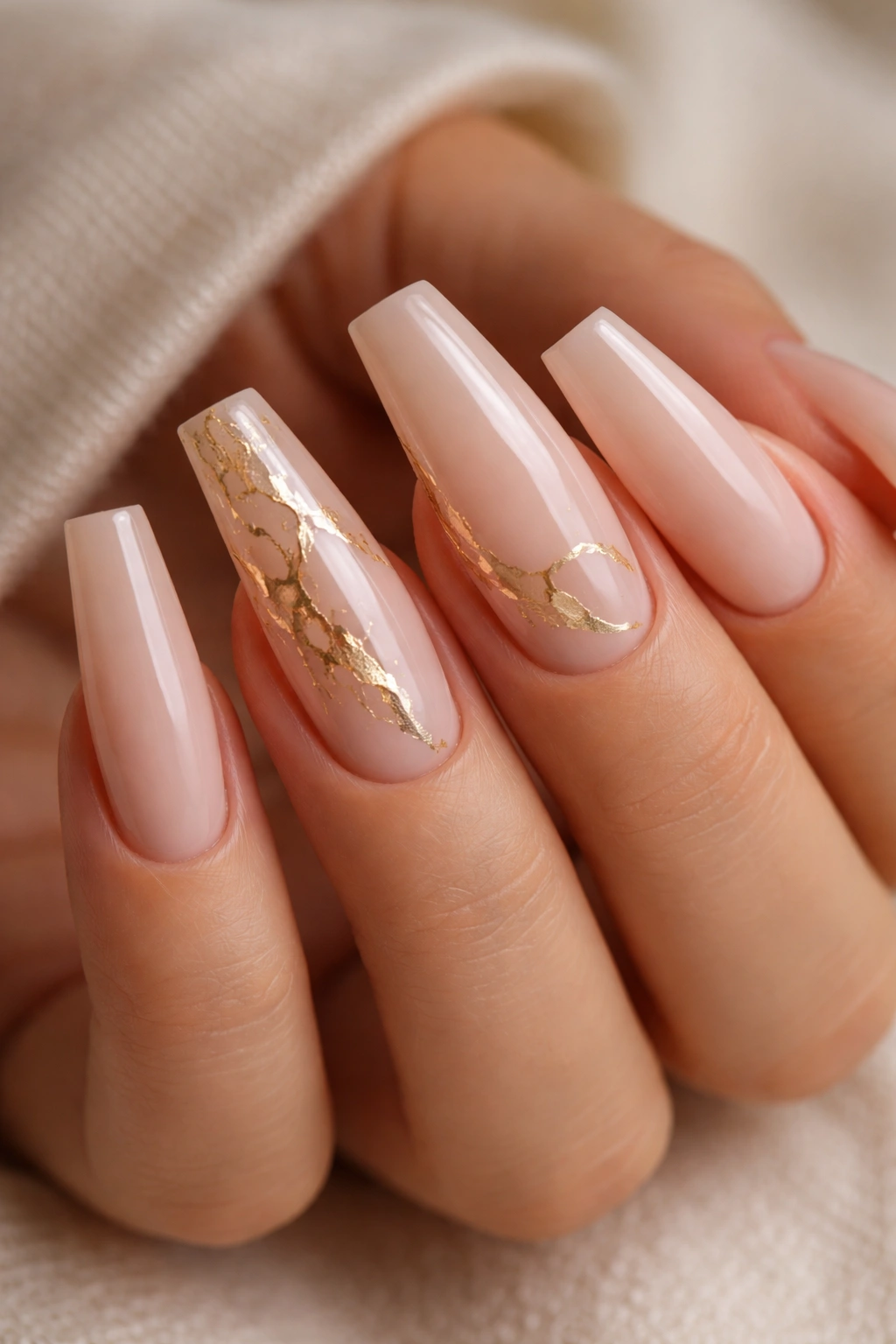 Long coffin nails with sheer nude base and delicate gold foil veins