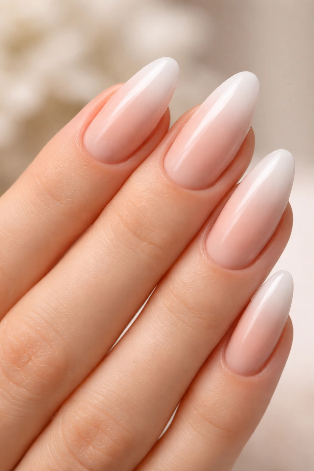 Close-up of nude-to-white French ombre almond nails with soft tip fade