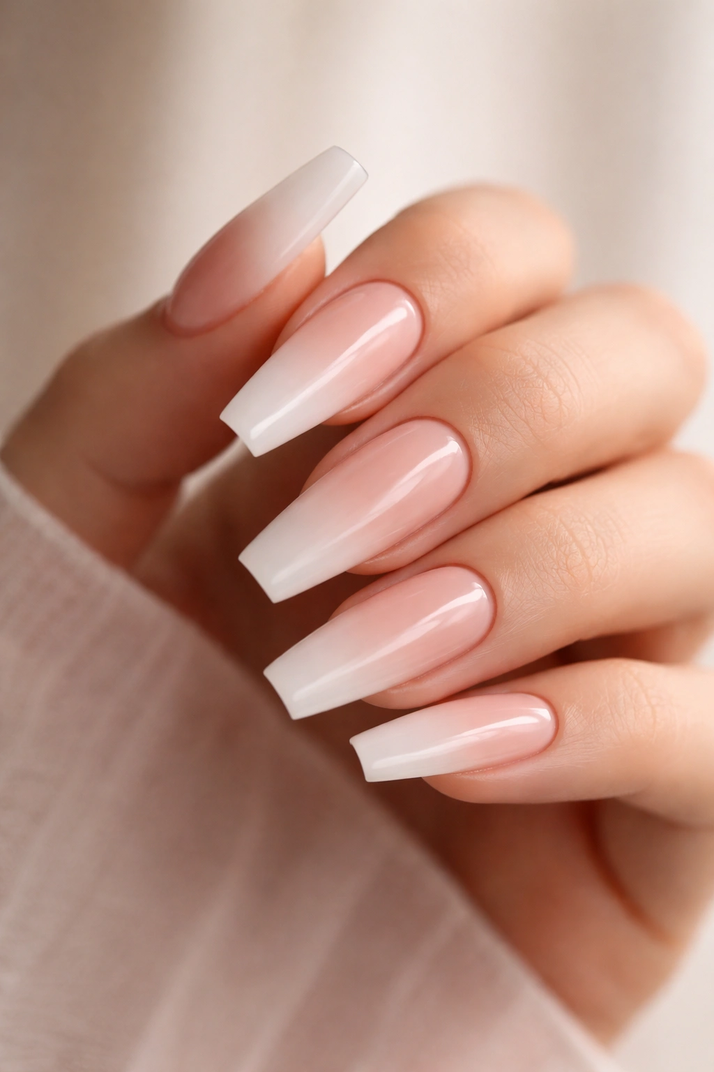 Close-up of nude ombre coffin nails with a soft pink to milky gradient on a hand