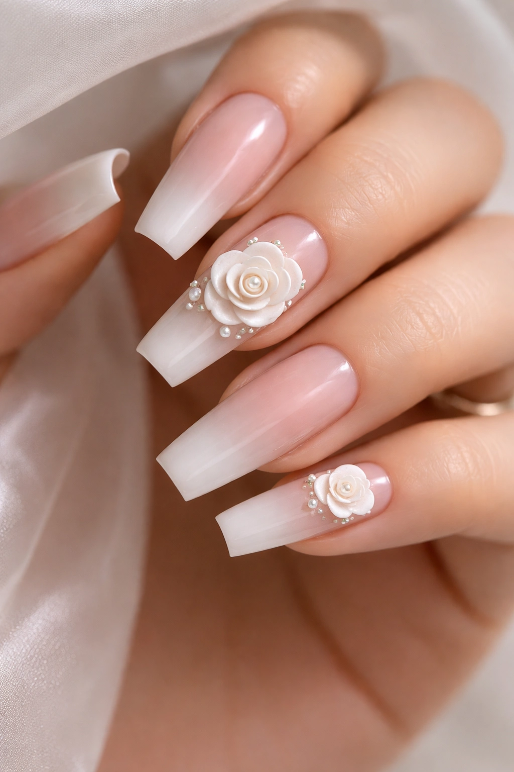 Nude ombre coffin nails with sculpted white roses on ring finger