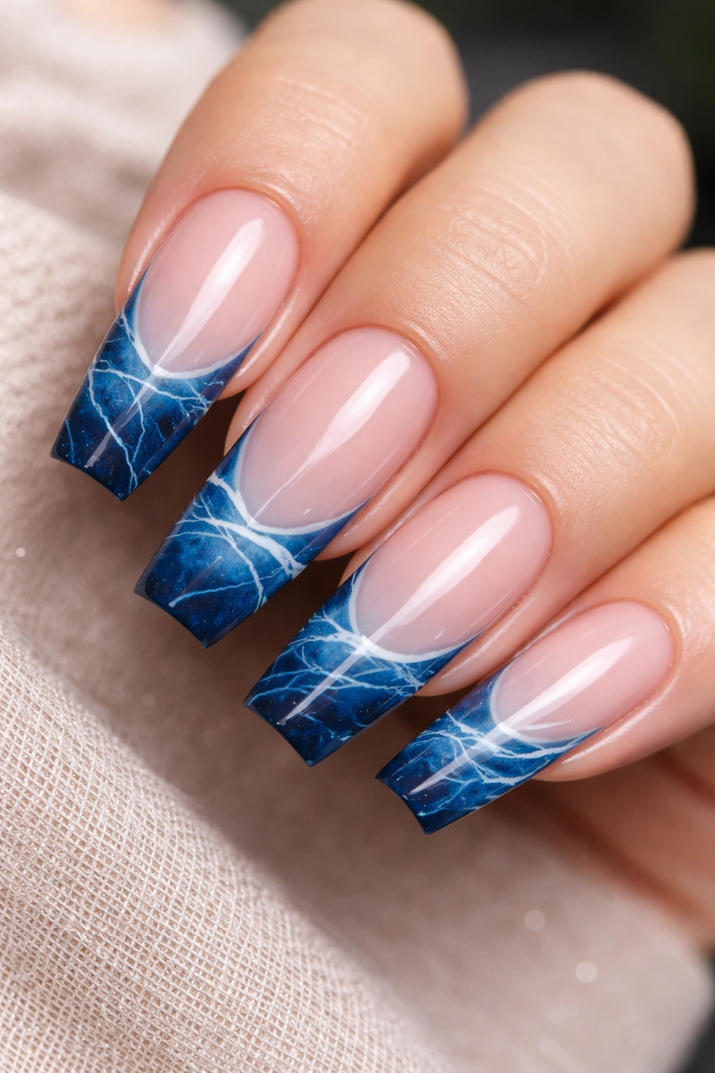 Close-up of ocean marble French tips with fine white veins on coffin nails.