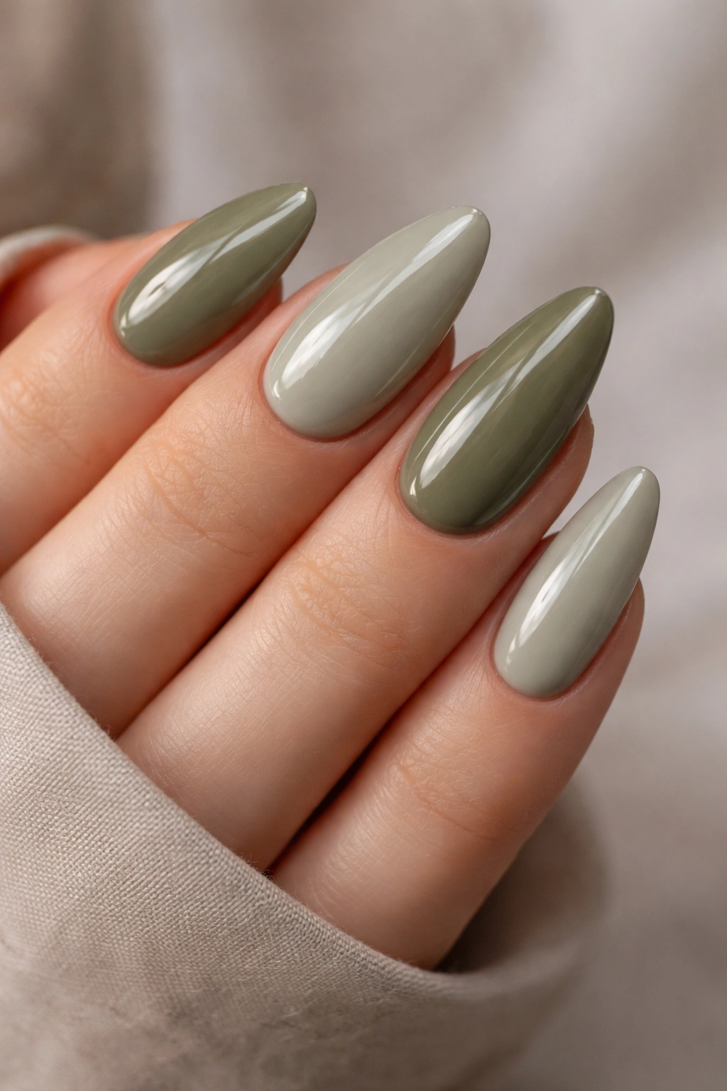Close-up of almond-shaped nails in olive and sage tones with a glossy finish