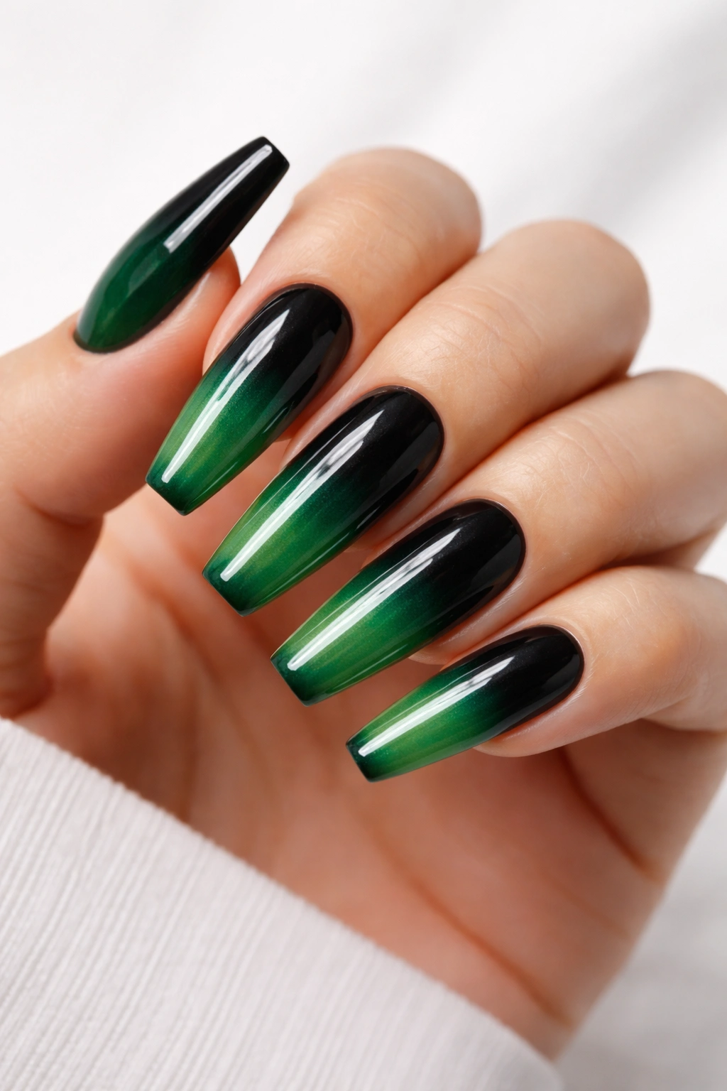 Close-up of black-to-green ombré coffin nails with a glossy gradient