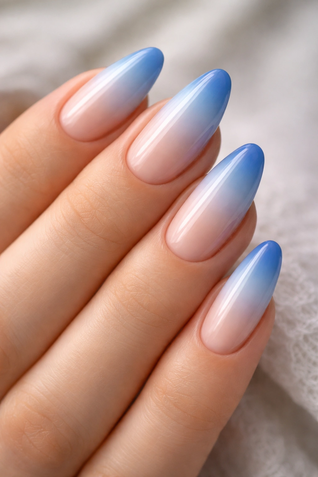 Almond nails with blue ombre tips gradient from pale to deep blue