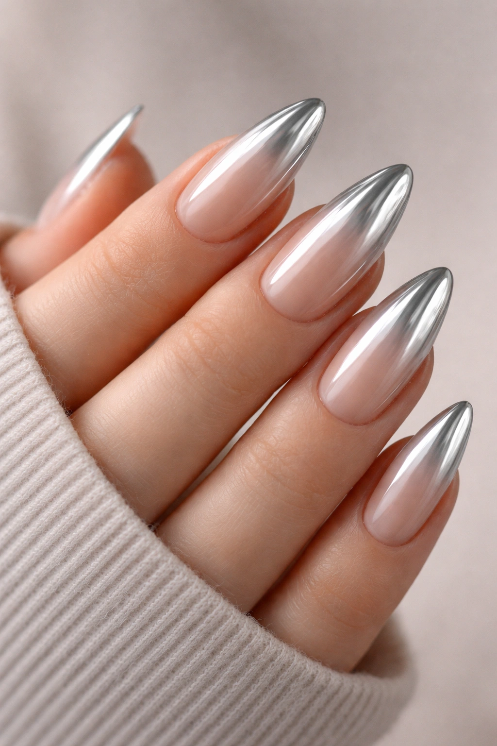 Close-up ombré chrome almond nails with nude base fading to silver