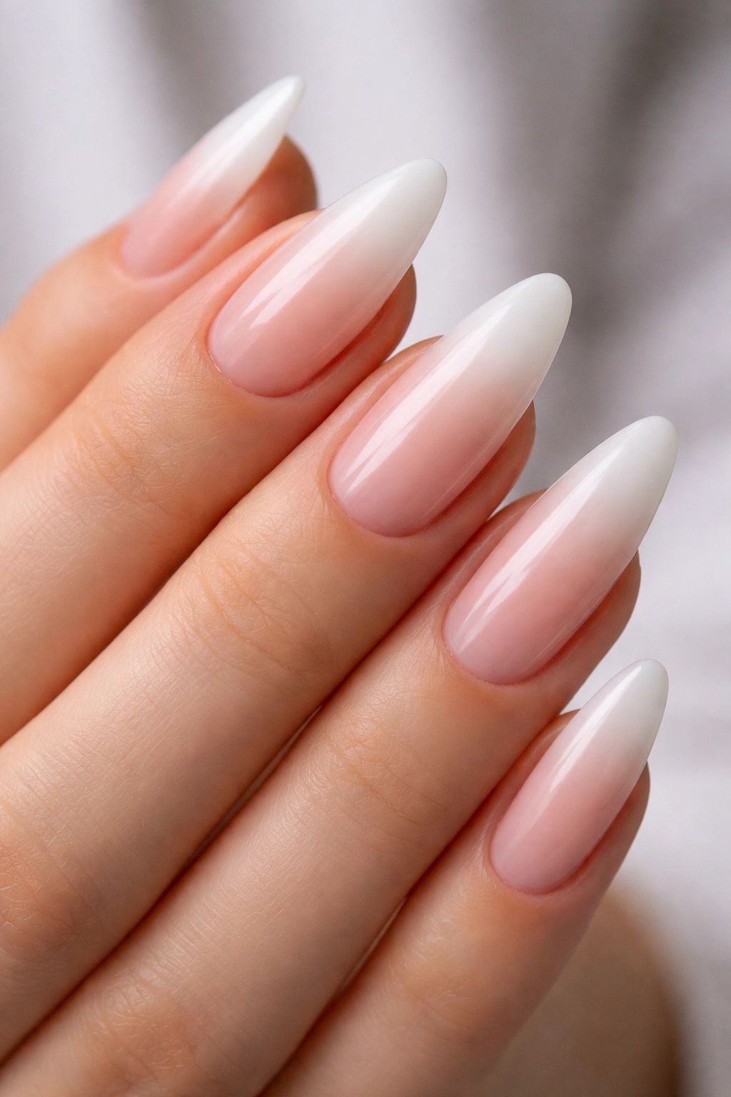 Close-up of long almond nails with a nude-to-white ombré tip