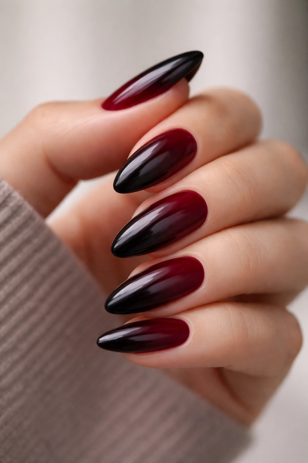 Close-up almond nails with black cherry ombre fade from deep red to near-black.