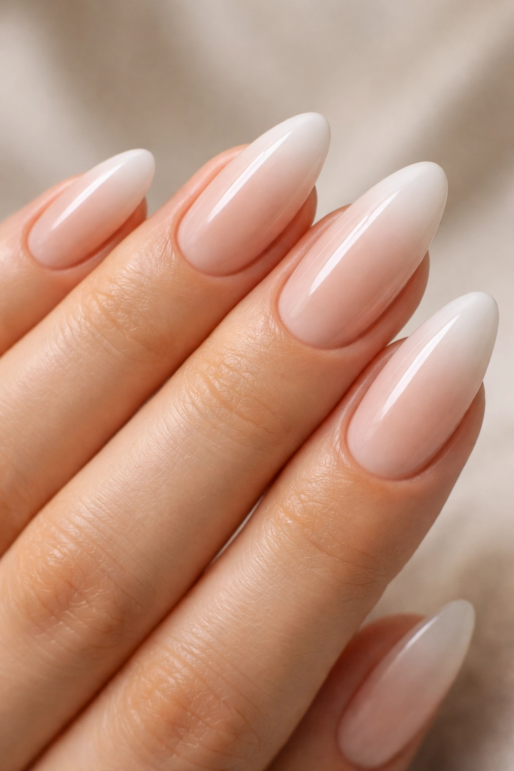 Almond nails with a soft nude-to-white ombré fade on the tip.