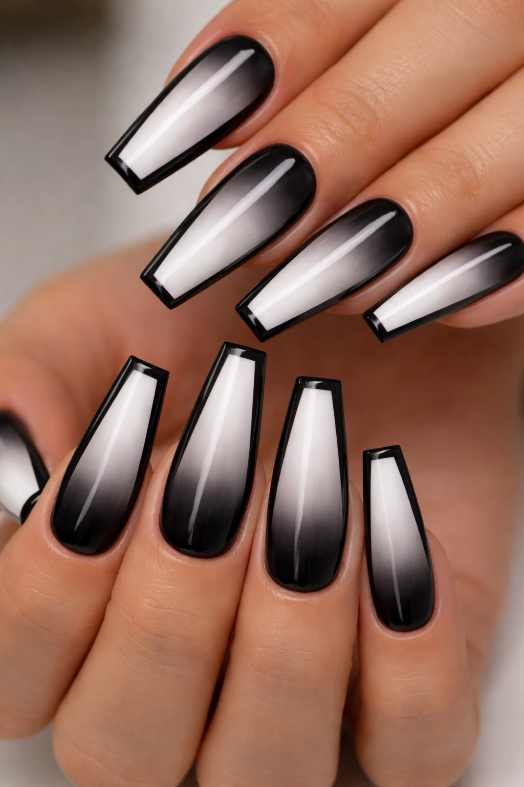 Close-up of coffin nails with black-to-white ombré and glossy outline