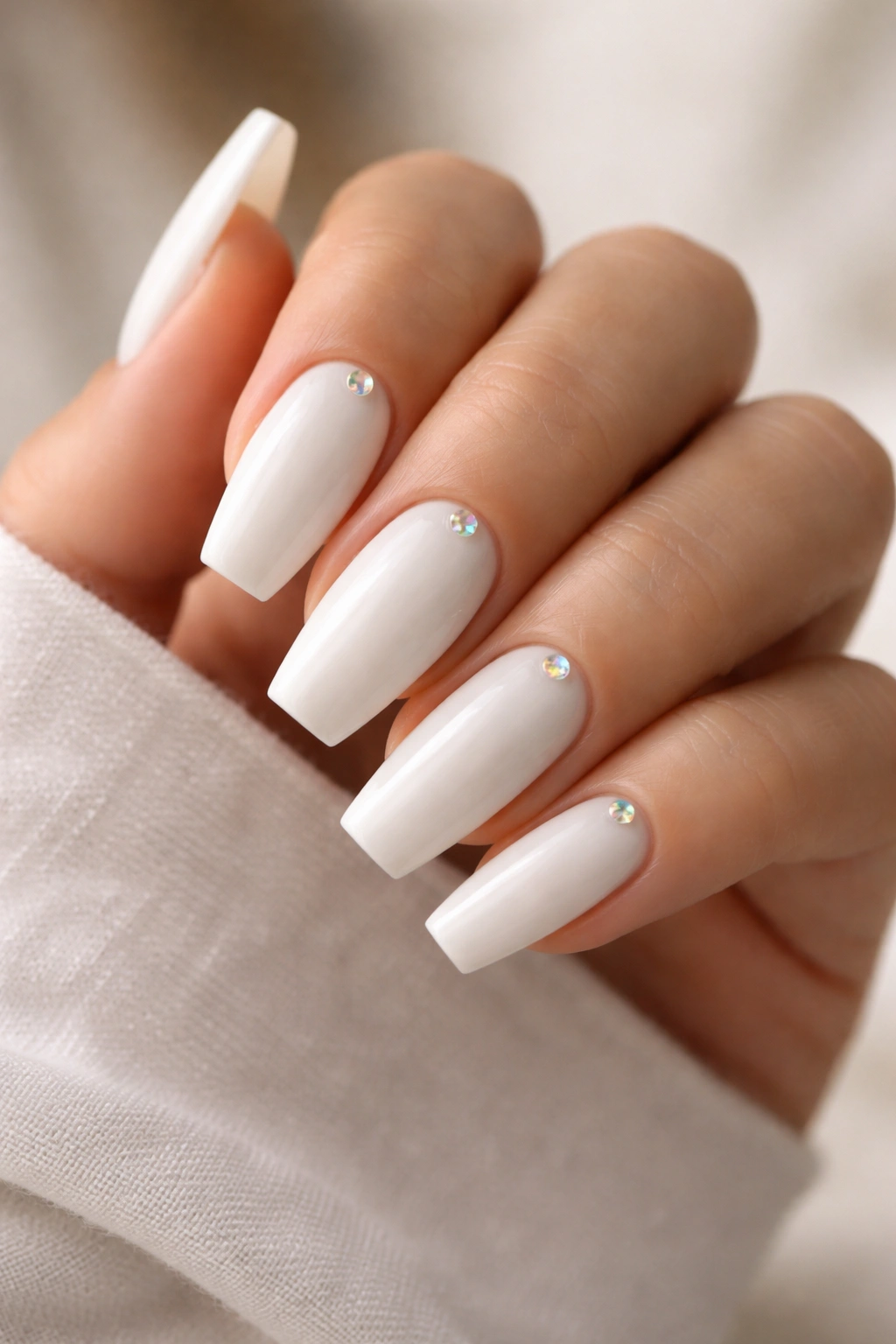 Soft white coffin nails with tiny opal dot accents near the cuticle