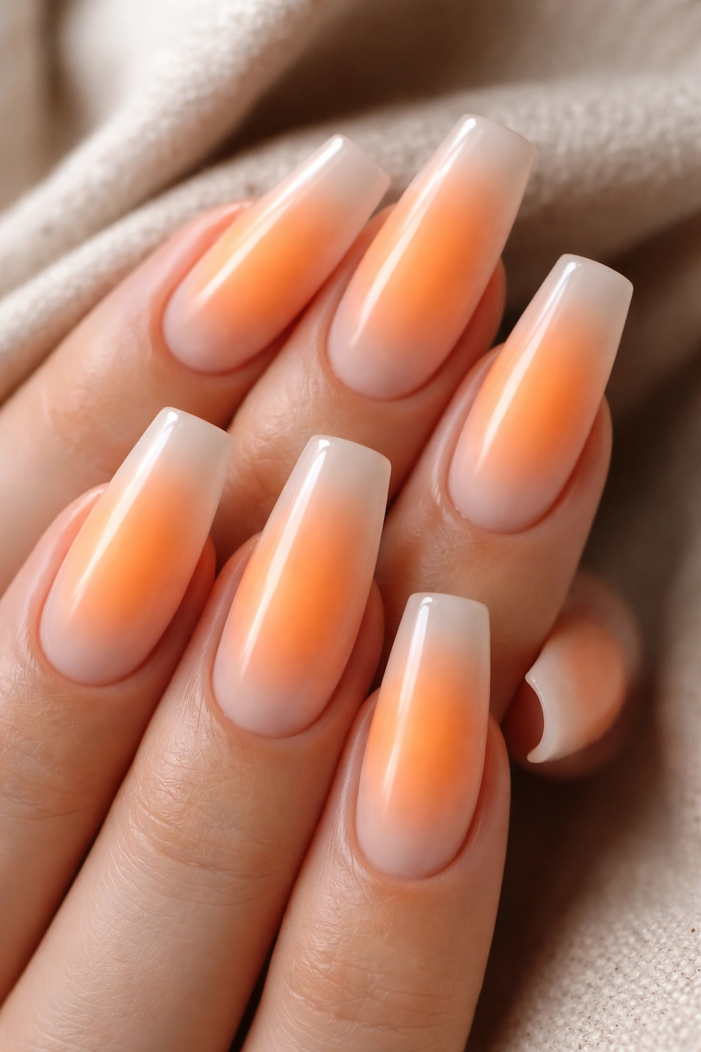 Orange aura coffin nails with soft central glow over milky base