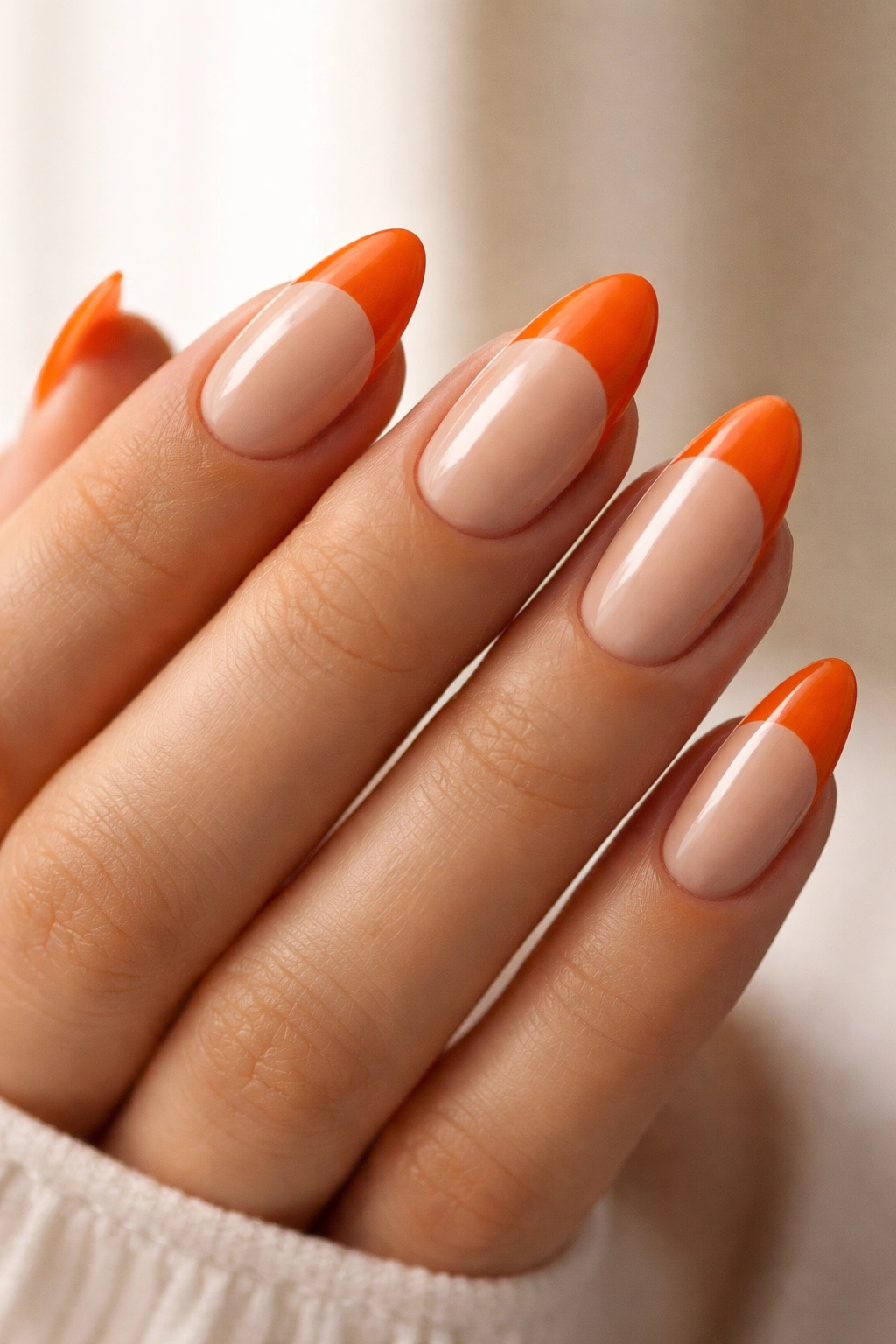 Almond nails with orange half-moon at base over nude