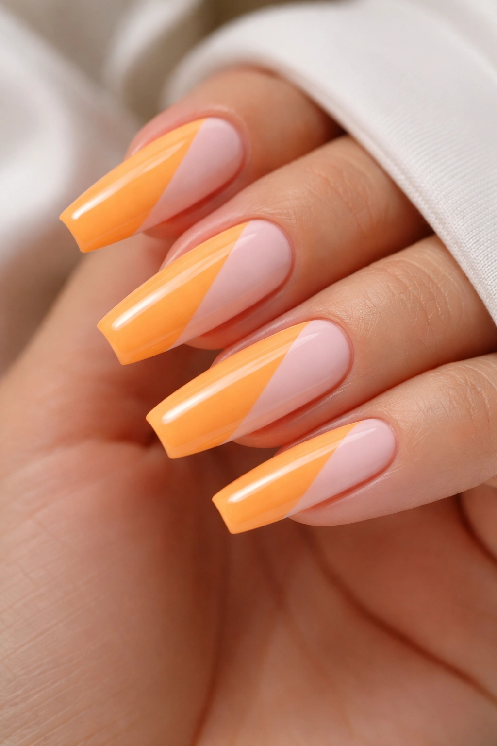 Close-up of cream sherbet orange and pale pink color-block coffin nails