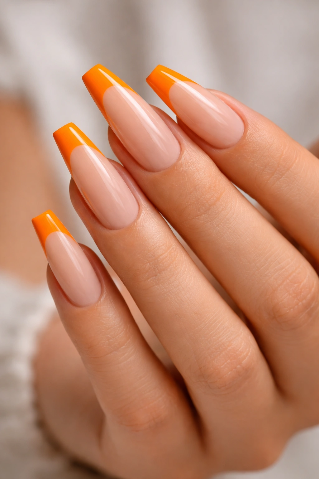 Nude-based coffin nails with orange French tips