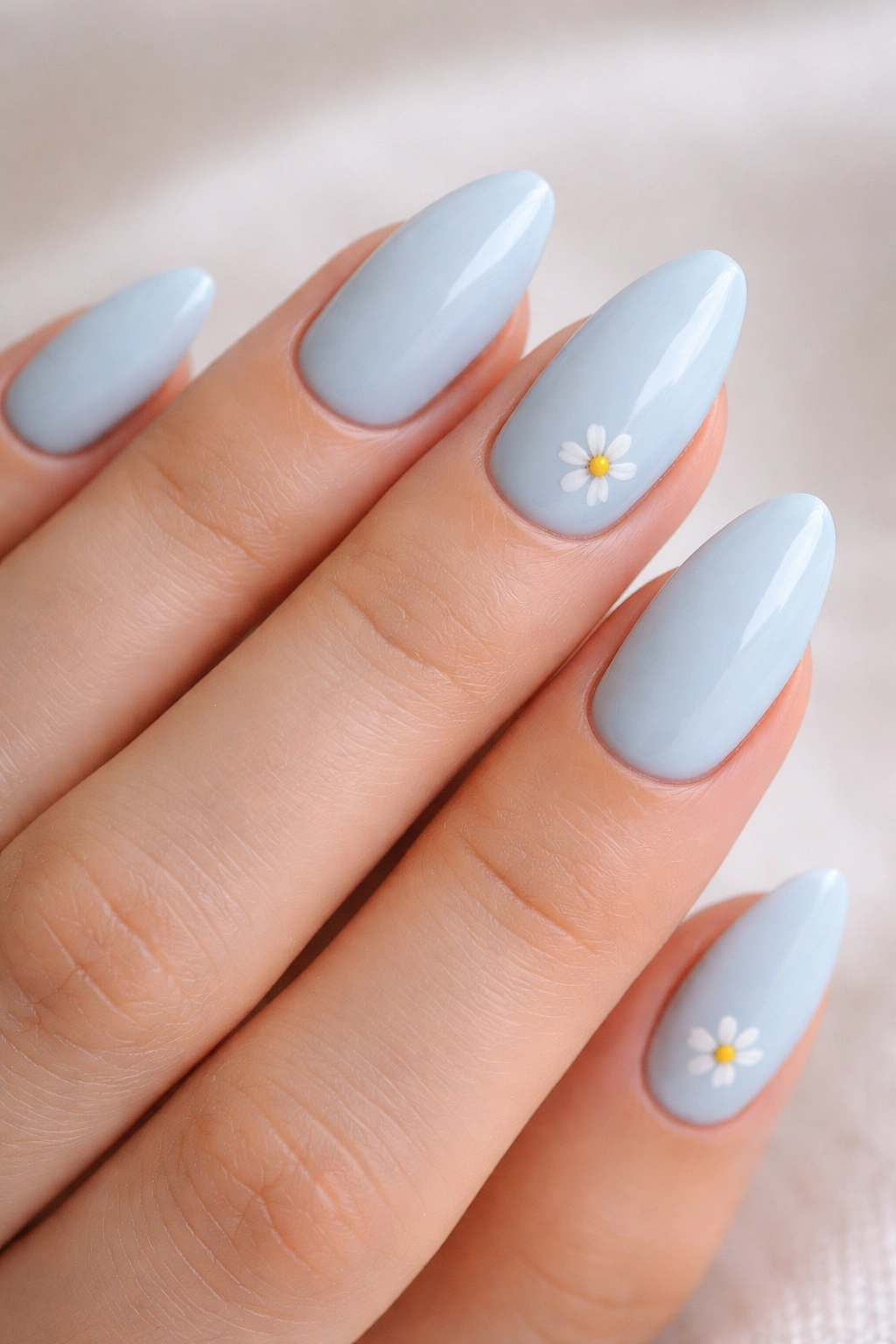 Close-up of almond nails with pastel blue base and tiny white daisies