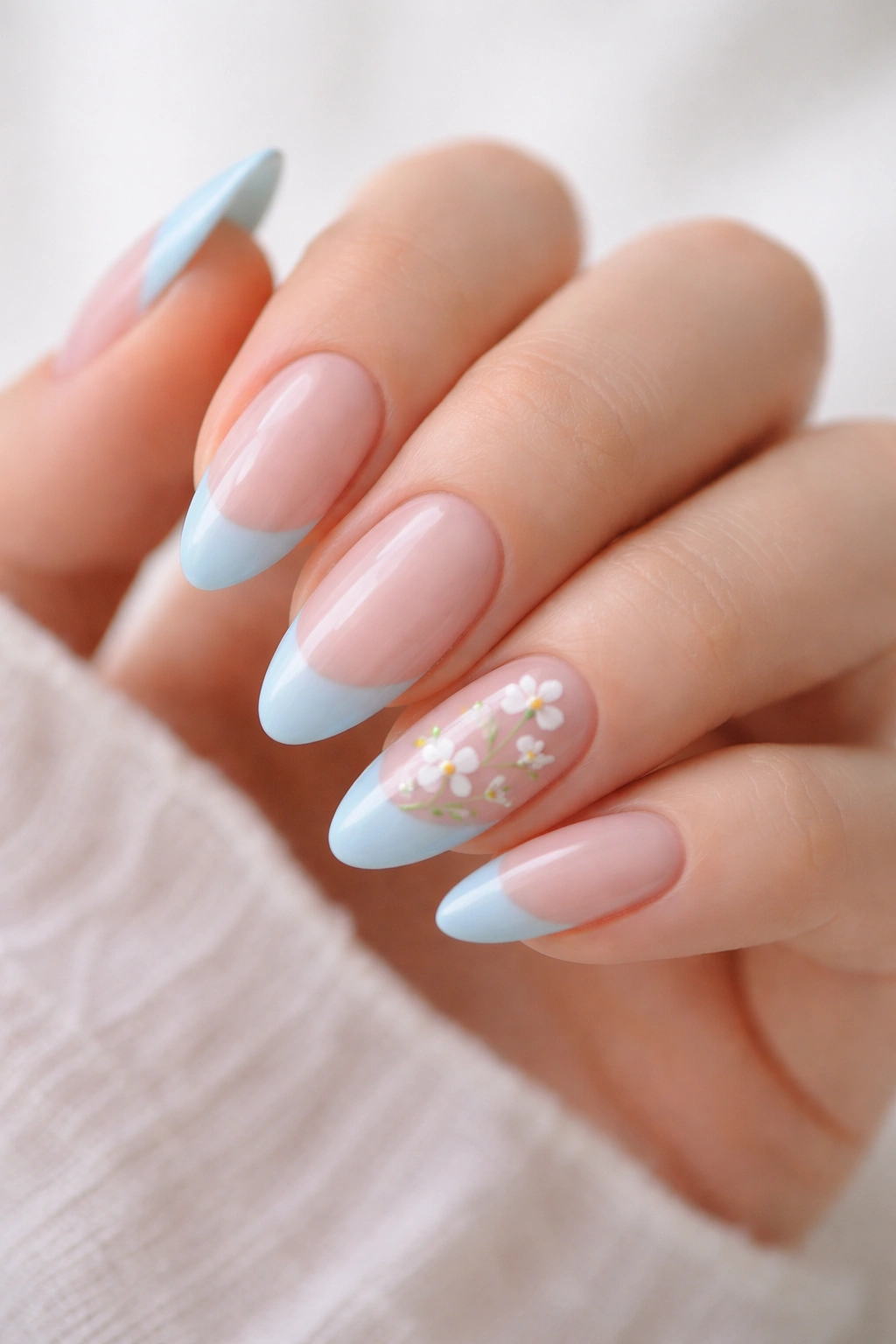 Pastel blue tips with tiny floral details on almond nails.